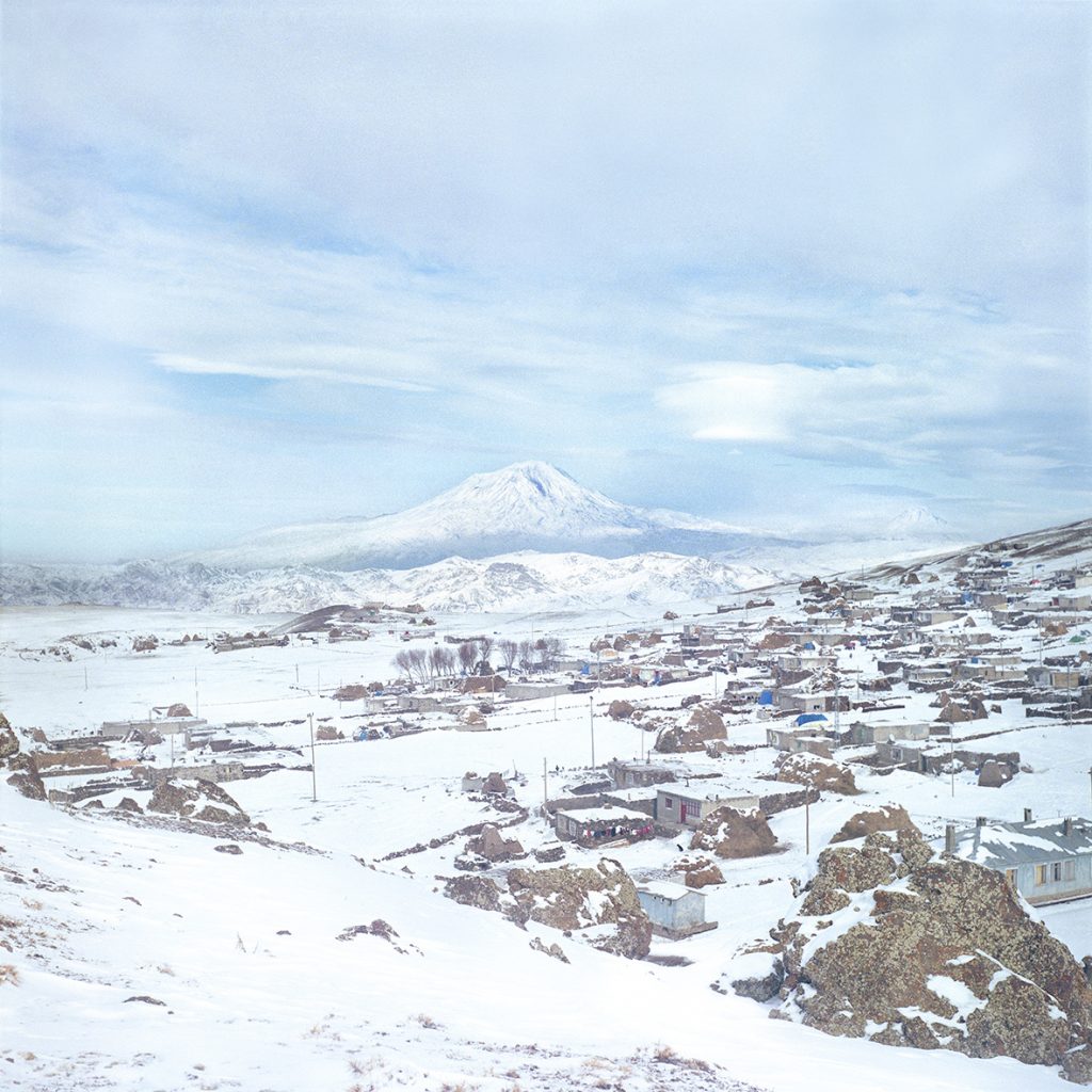 A photograph of a snowy town in the foreground, with a mountain in the distance