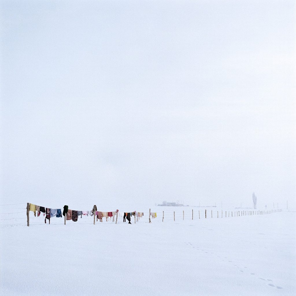 A photo of racks covered in clothes hanging in the snow.