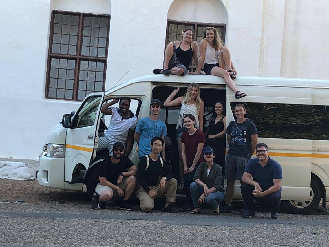A group of 11 posing with Albert in front of a white van