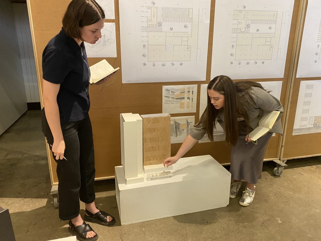 Two women looking at a model of a building.