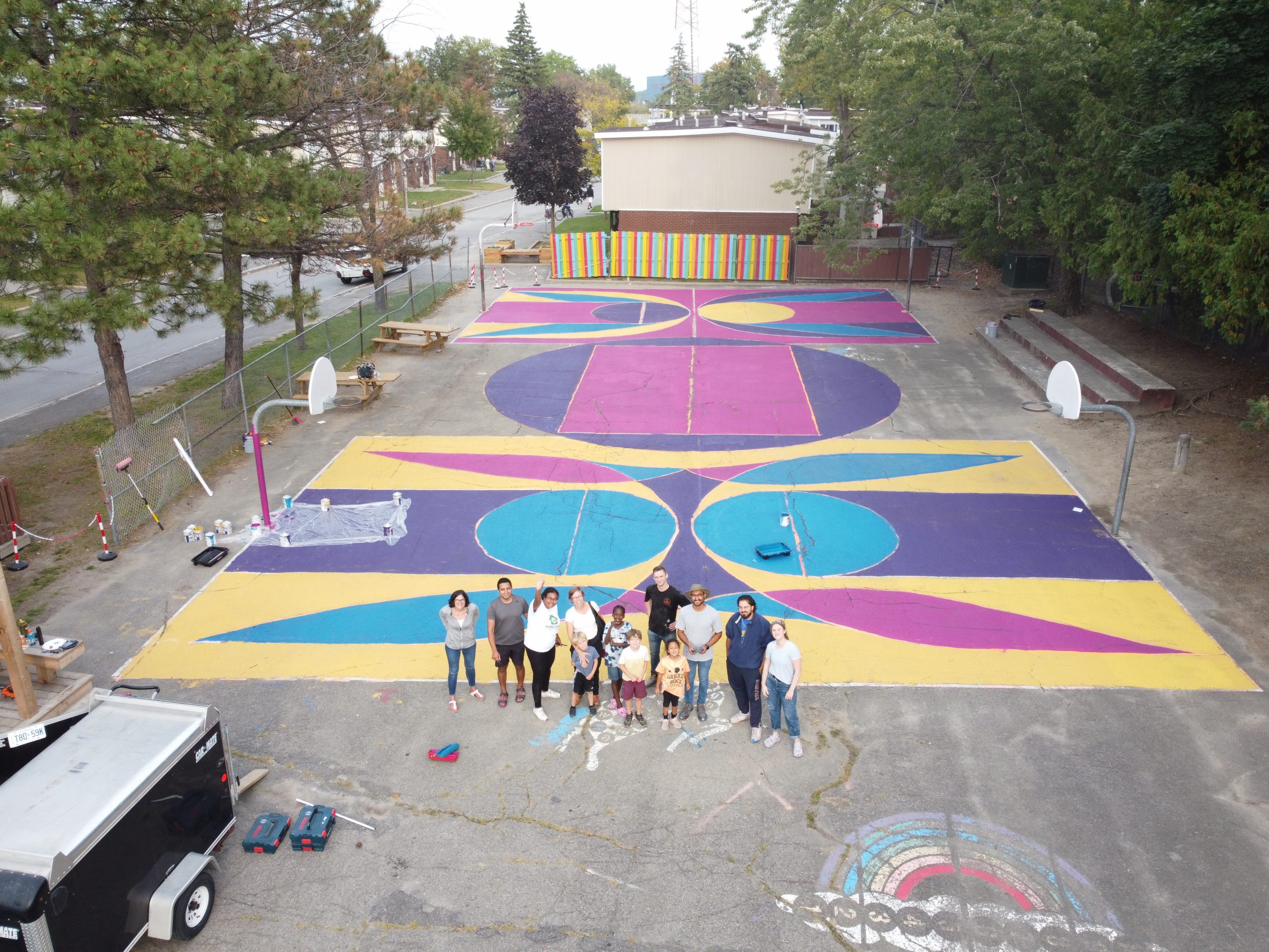 A group of people standing on a colorfully painted basketball court.