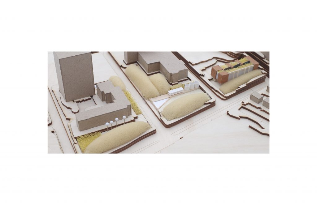 Physical architectural model with various buildings, landscaping, and topography details.
