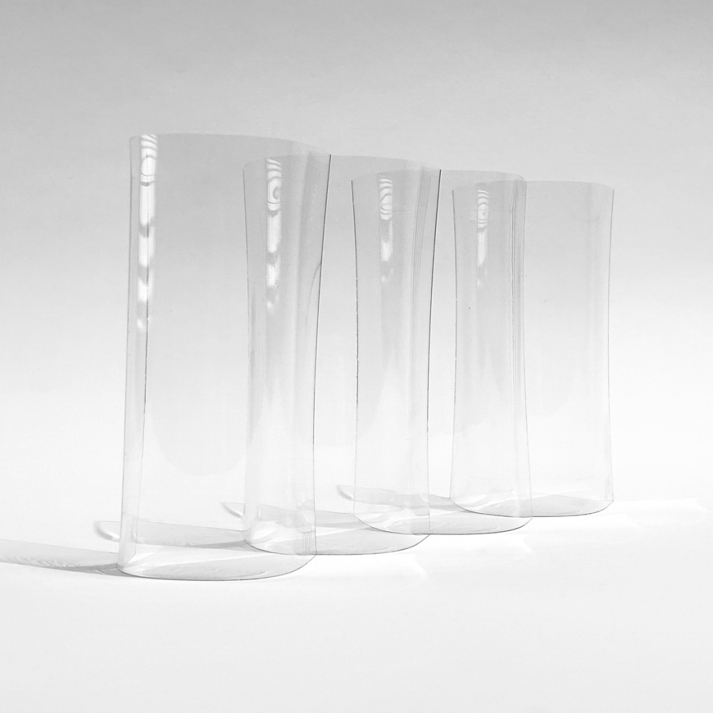 a black and white photograph showing a series of upright, curved glass sheets placed in a row, creating a repetitive, wavelike pattern.