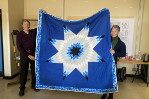 One man and one woman holding up a blue blanket