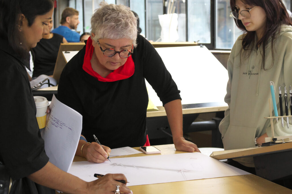 A prof correcting a students design and drawing.