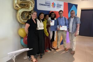Group of people standing for a photo. in front of decorations about Community Services. Two members of Community Services, 3 members of Action Lab including a professor, and an addition Urbanism professor.
