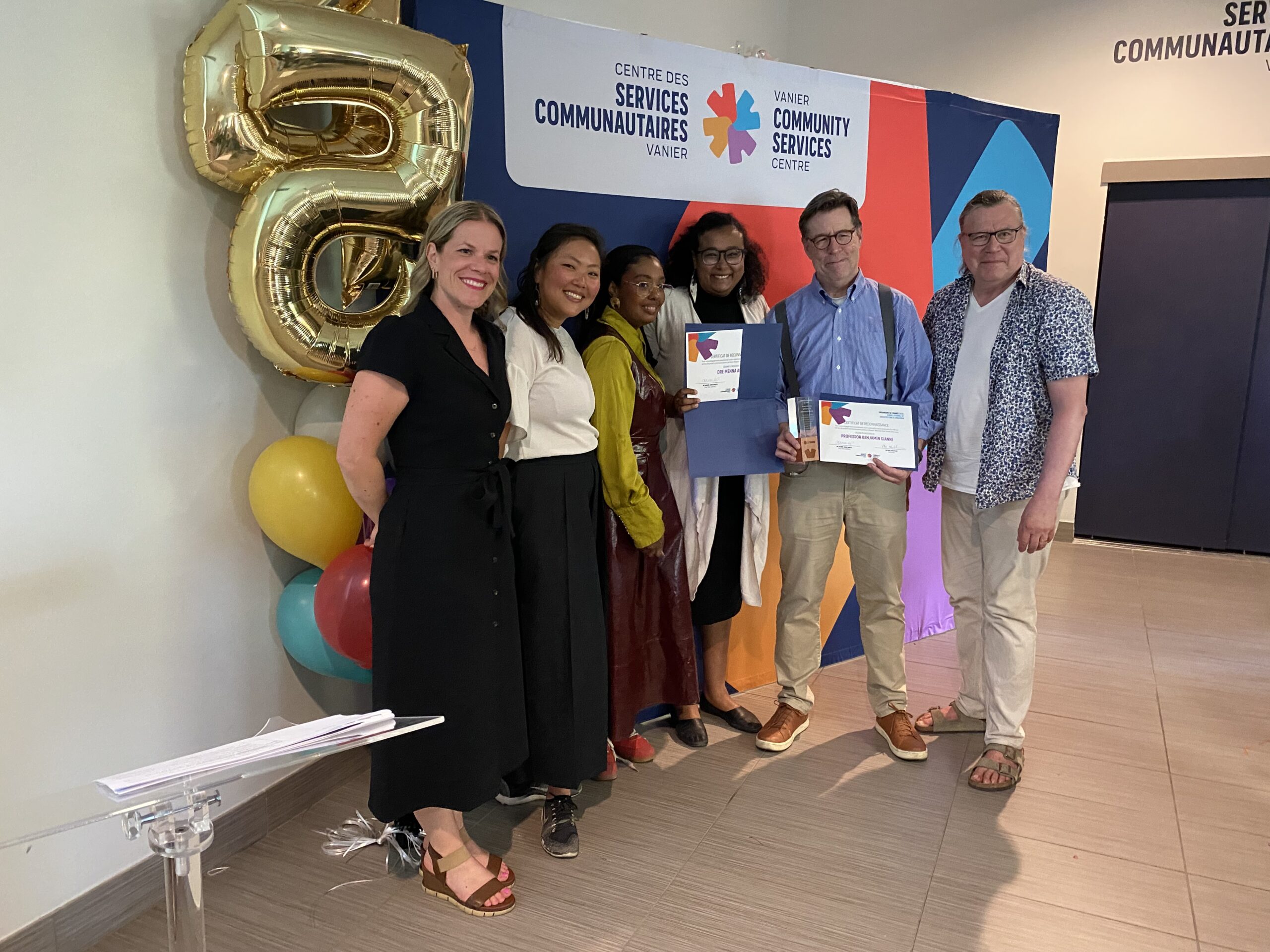A group of people standing receiving an award with Community services.