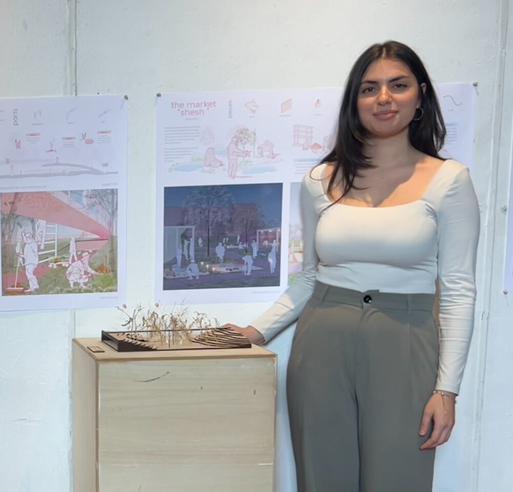 An Architecture student standing next to their posters and model for their final project.