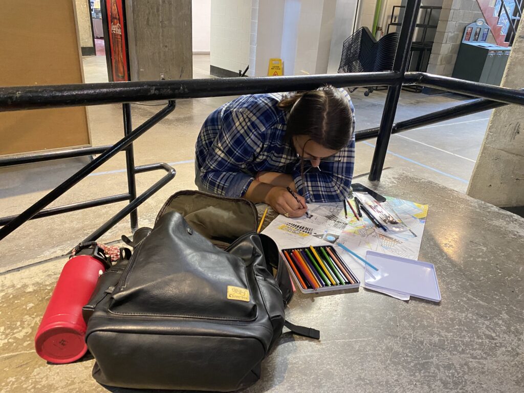 Student sketching on the floor with coloured pencils and drawing tools