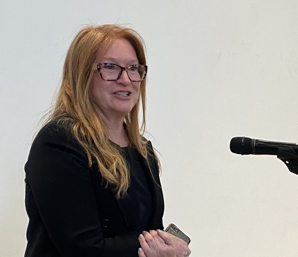 Fiona Murray standing at a microphone, speaking during the event.