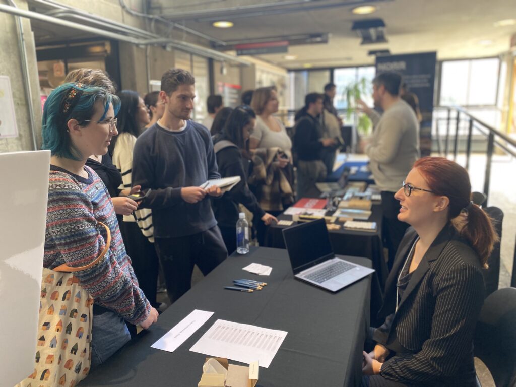 Students speaking with a seated employer at a table