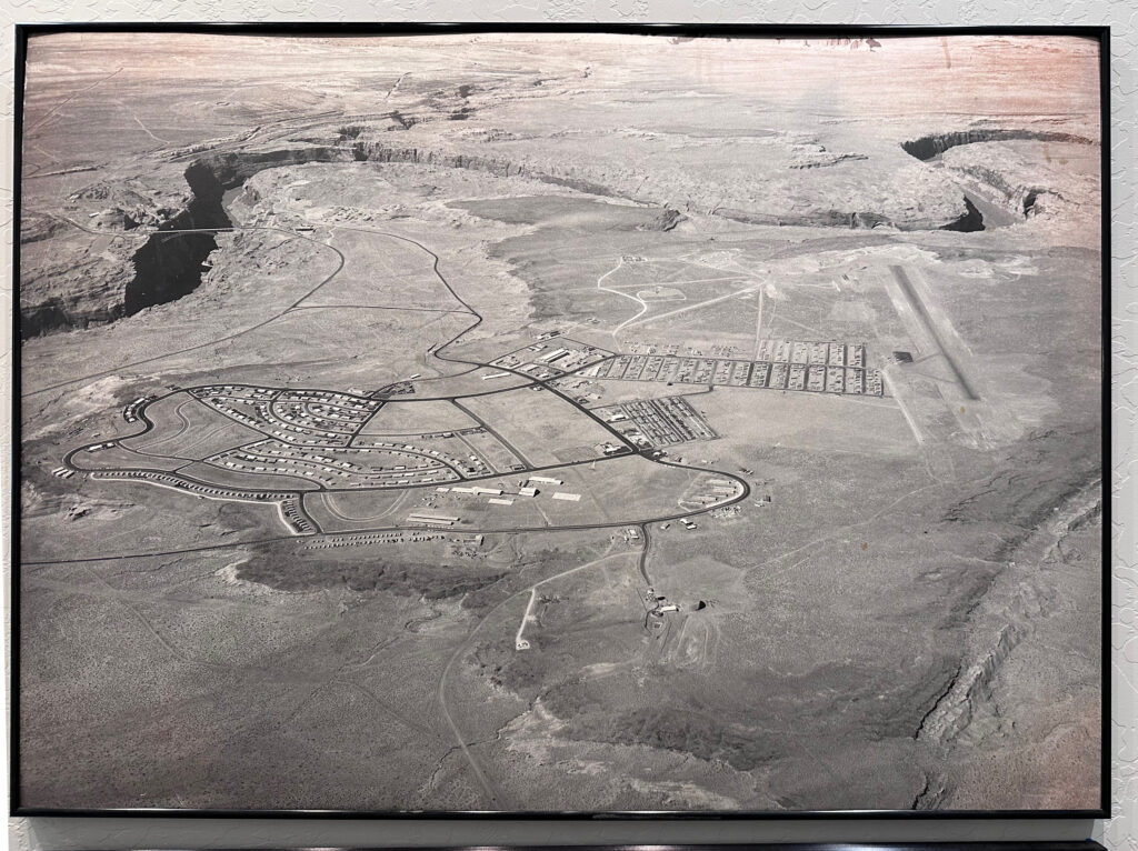 Aerial view of early Page, Arizona, showing gridded housing, roads, and Glen Canyon edge in surrounding desert landscape.