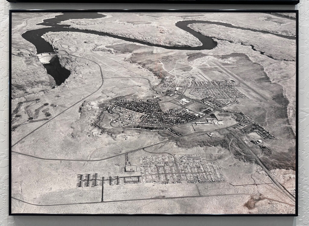 Aerial view of Page, Arizona, showing Glen Canyon Dam, river, gridded neighborhoods, and nearby desert airstrip.