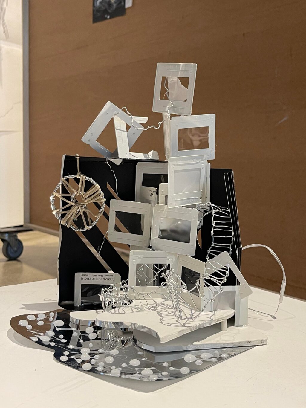 Model made of slide frames, wire mesh, and mirrored base with white dots.