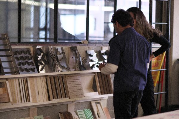 Two people standing in front of a wall of material samples, discussing the displayed pieces