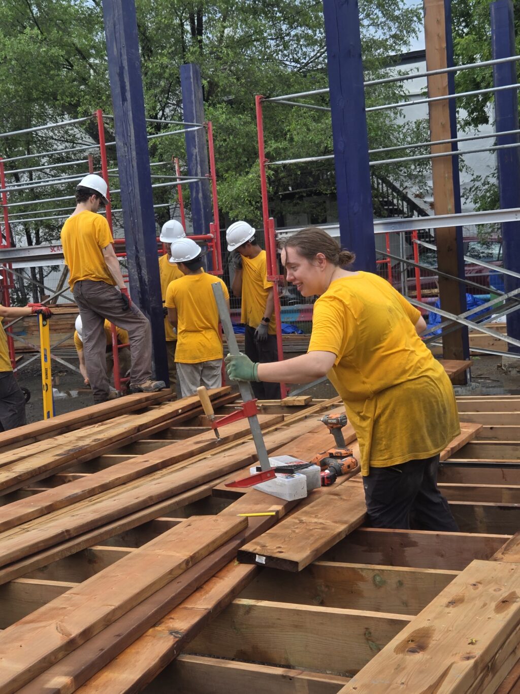 Students installing wooden decking boards as part of the Vanier Hub structure.