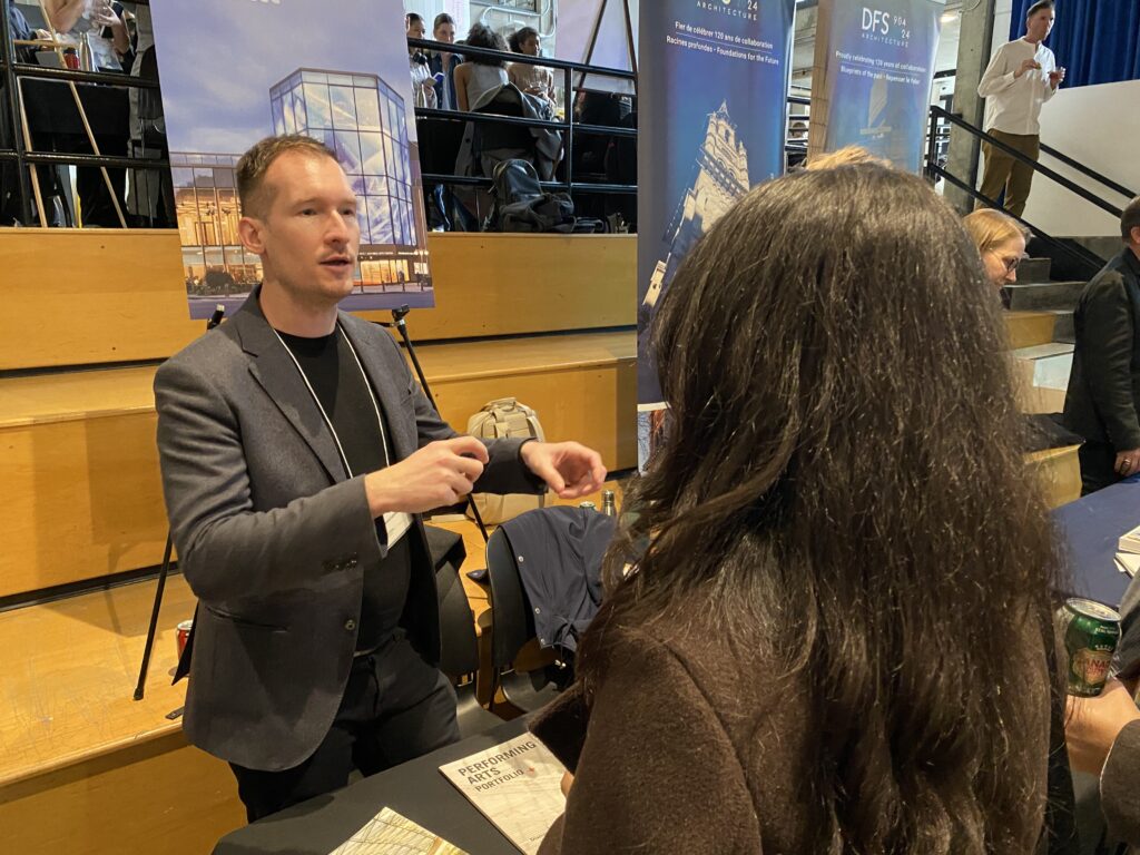 Arne Suraga in blazer gesturing while speaking to a student