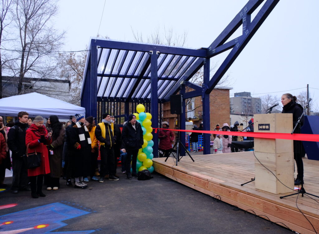 Anne Bordeleau addressing the crowd at the Vanier HUB opening beside the red ribbon.