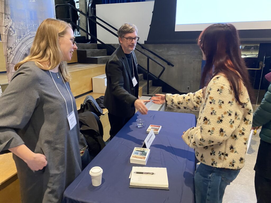 Two firm representatives reach forward to greet a student across the table during a conversation.