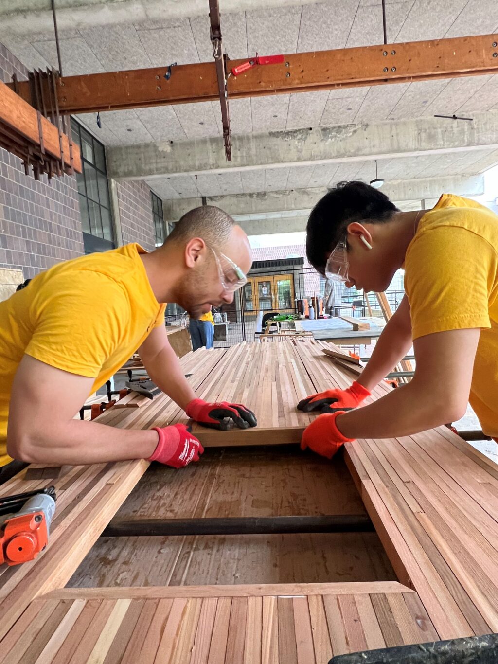 Students assembling narrow wooden slats to form a tabletop for the HUB’s outdoor furniture.