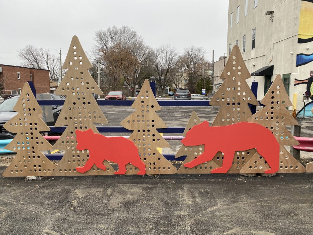 Red animal cut-outs installed in front of student-built wooden tree panels at the HUB site.