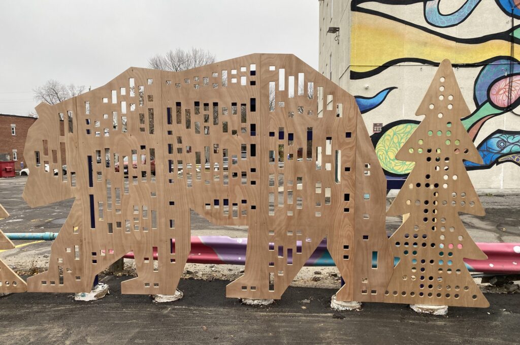 Large perforated wooden bear panel installed as part of the HUB’s student-built landscape elements.