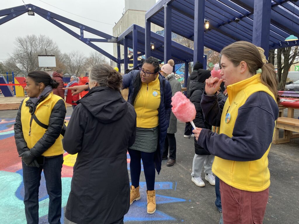 Anne Bordeleau, Menna Agha and students talking and eating cotton candy under the blue-framed structure at the opening event.