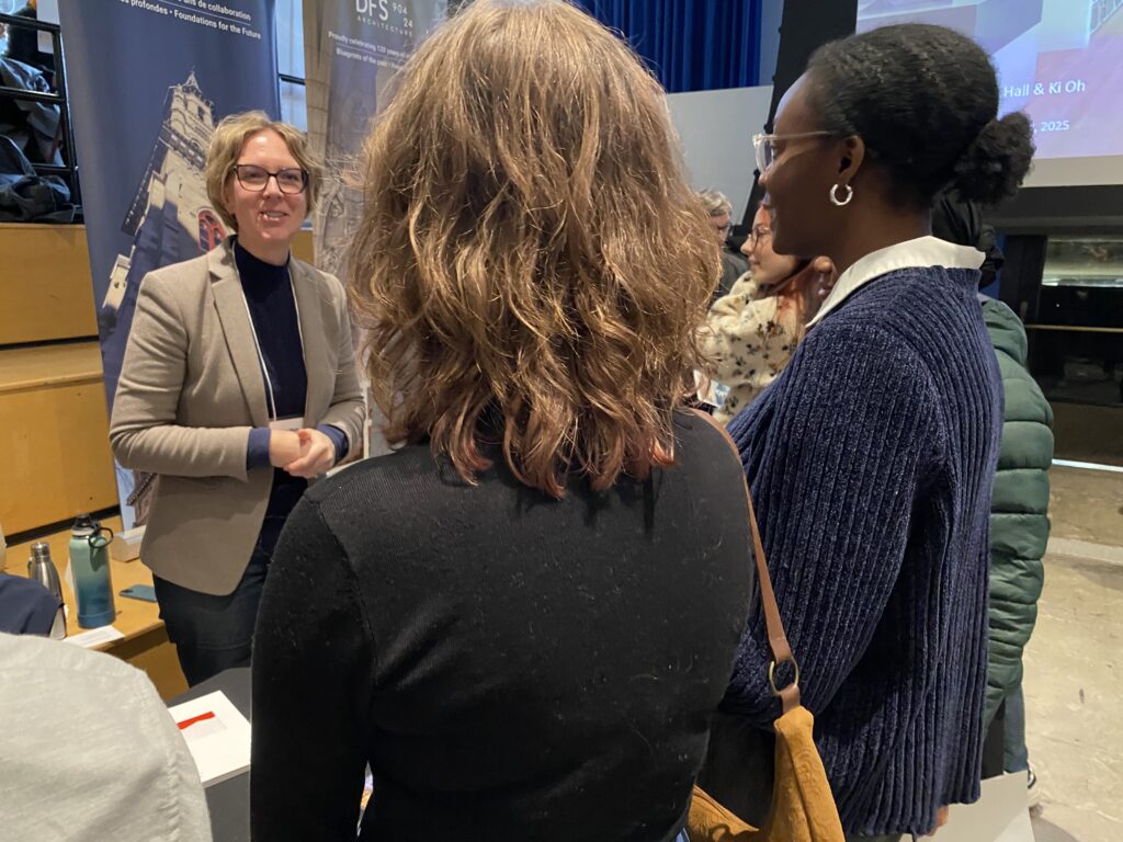 Tara Plett talking to two students with posters in the background.