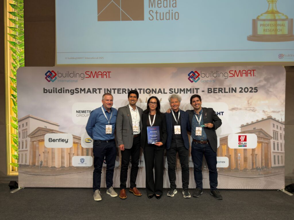 Five people stand on stage in front of a backdrop reading “buildingSMART INTERNATIONAL SUMMIT – BERLIN 2025”.