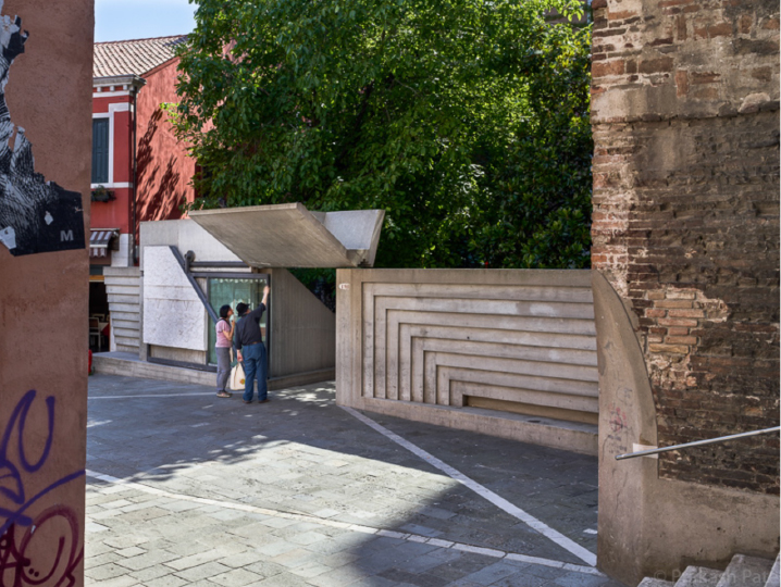 Concrete entrance element with stepped profiles inserted into a historic brick streetscape.